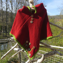 Poncho Coquelicot à capuche , couleur écru lègèrement chiné avec une bordure rouge pour les finitions. Au bas du poncho il y a des boutons en bois que donne une impréssion de fleurs.